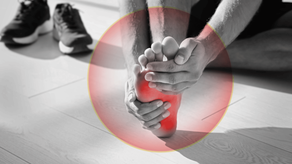 Person gripping foot in pain sitting on floor next to tennis shoes from plantar fasciatis