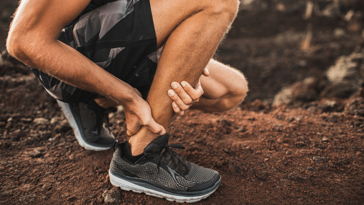 Man grasping ankle and achilles tendon in pain