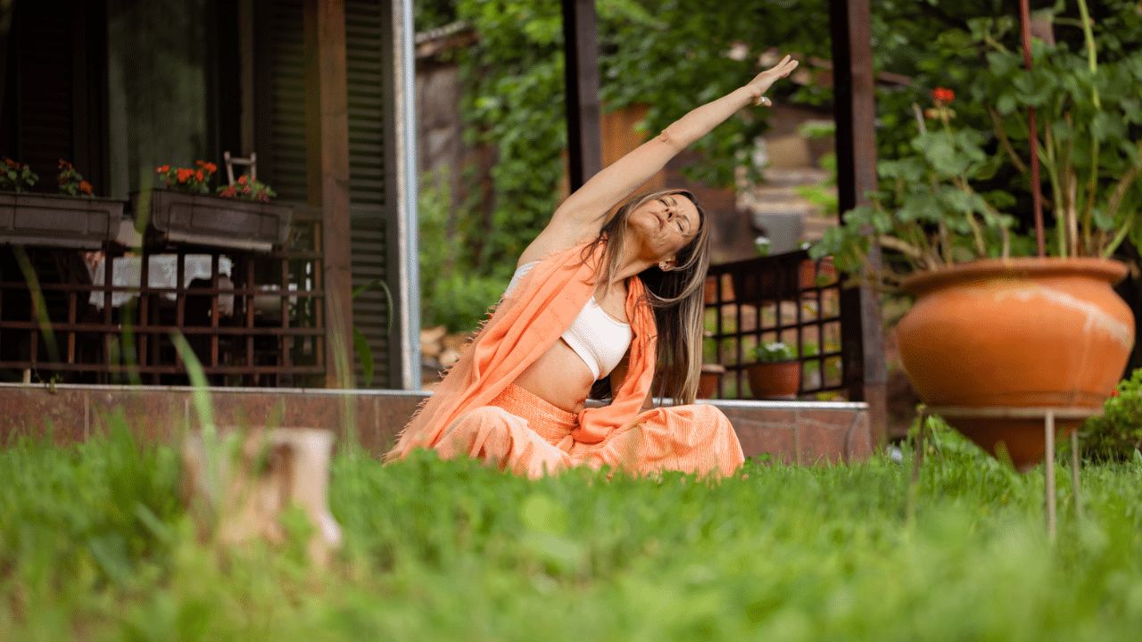 Woman sits cross legged stretching arm above head as part of the mind body connection
