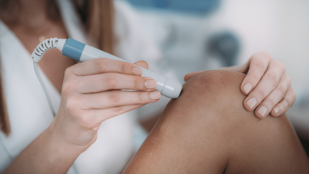 Specialist physical therapist using a cold laser treatment on a patient's knee for knee pain