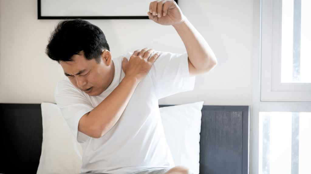 Man lifts up shoulder in pain before treating frozen shoulder with physical therapy
