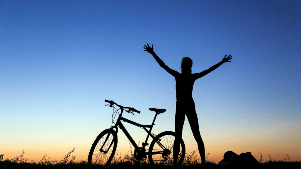 Person reaching for the sky next to their bike after a good workout as recommended by an Austin physical therapist for A Holistic Approach to Living with Peripheral Neuropathy