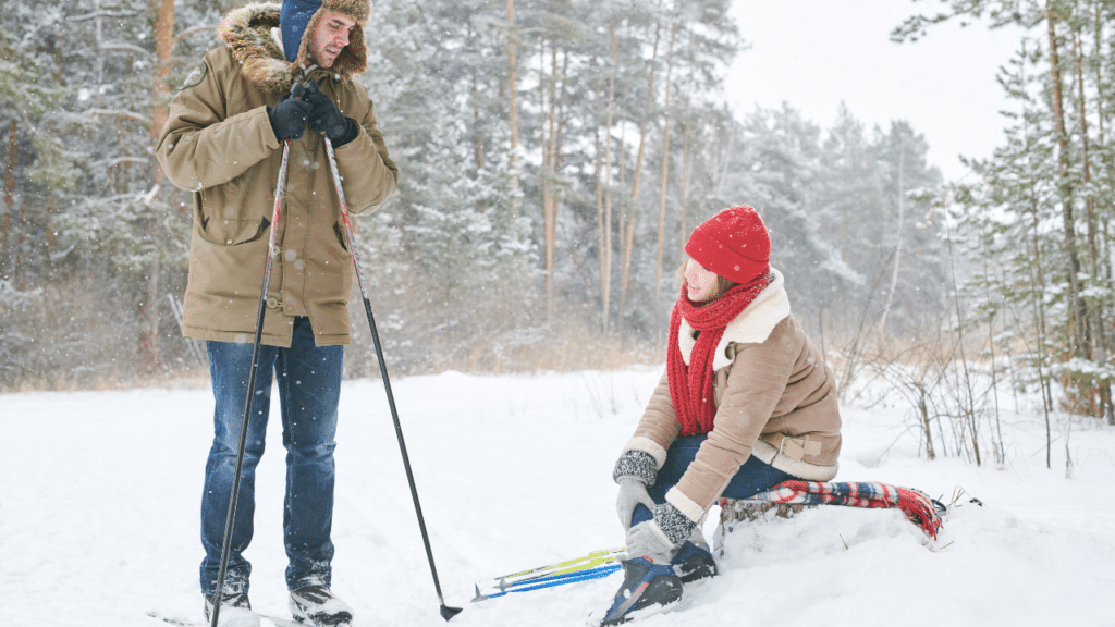 Woman holds ankle in pain while skiing with a man demonstrating Why Preseason Prep Matters for Ski Season