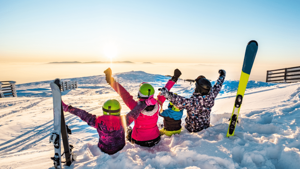Family sits on top of snowy mountain after learning the Top 10 Exercises to Prepare for Ski Season