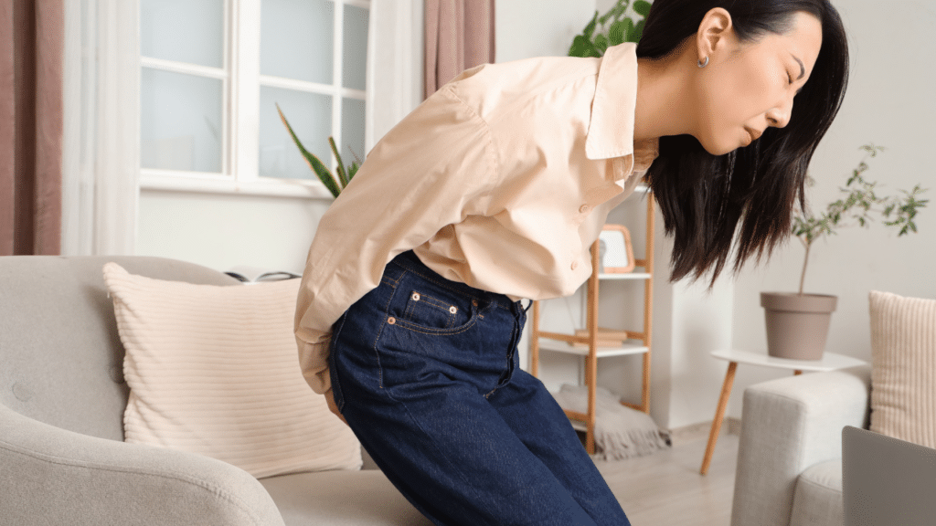 Woman holds tailbone when standing after sitting Buttock Pain When Sitting or Running? It May Be Proximal Hamstring Tendinopathy