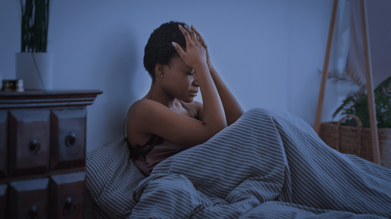 Woman sits up in bed unable to sleep and wonders Why Nerve Pain Gets Worse at Night