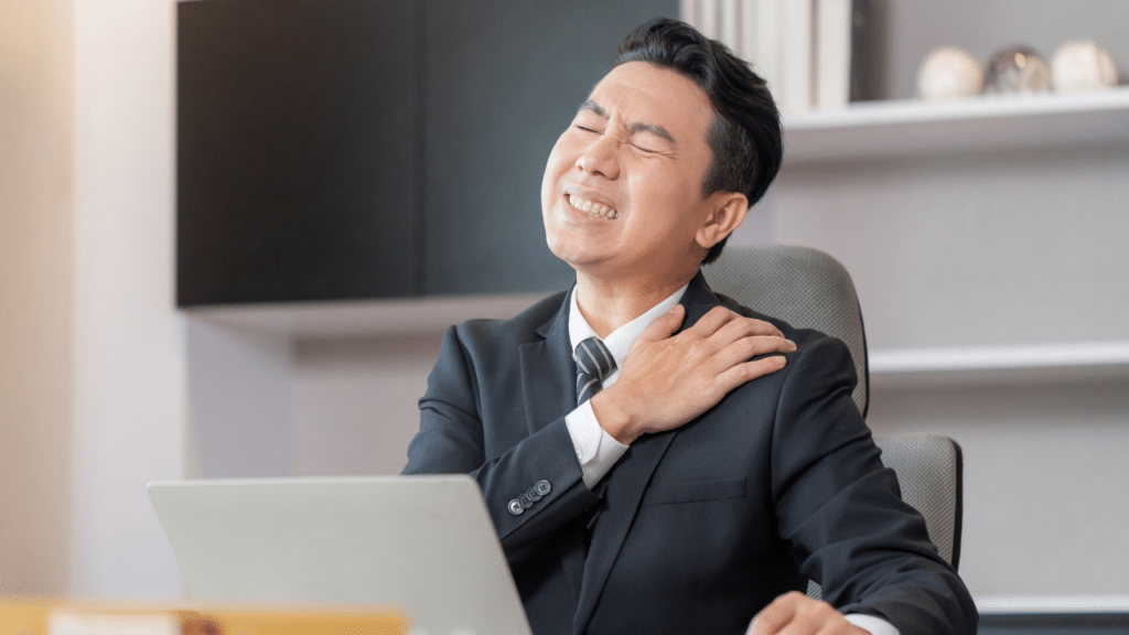 man holds shoulder in pain wondering why Your Tight Upper Back Is Wrecking Your Shoulders (3 Thoracic Spine Mobility Drills)