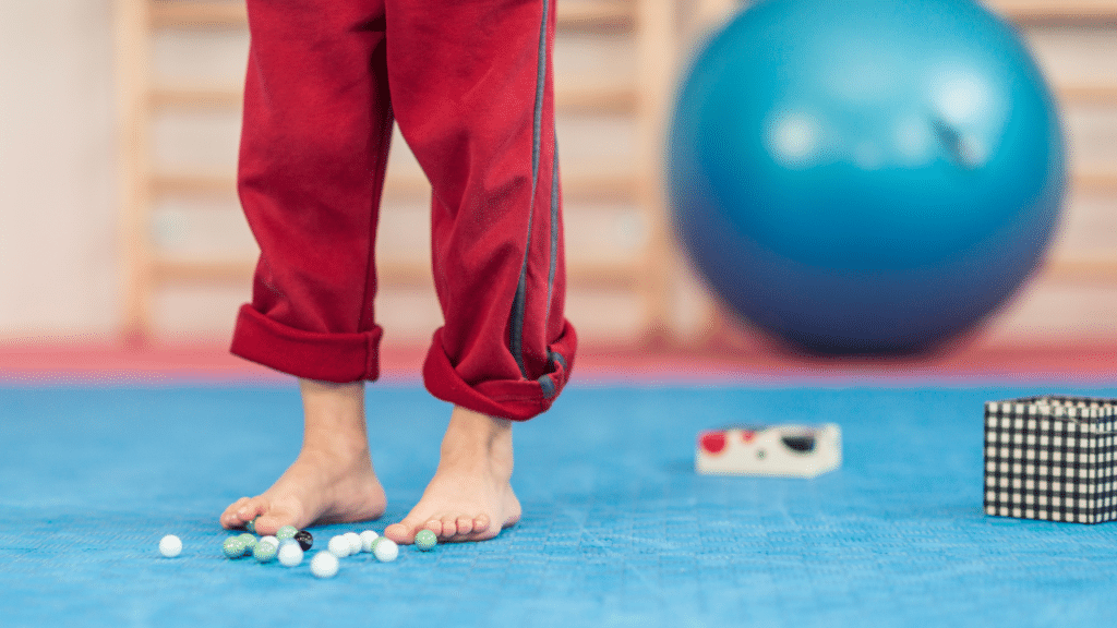 person attempts to pick up marbles with feet as part of weak feet in-home physical therapy austin tx.png